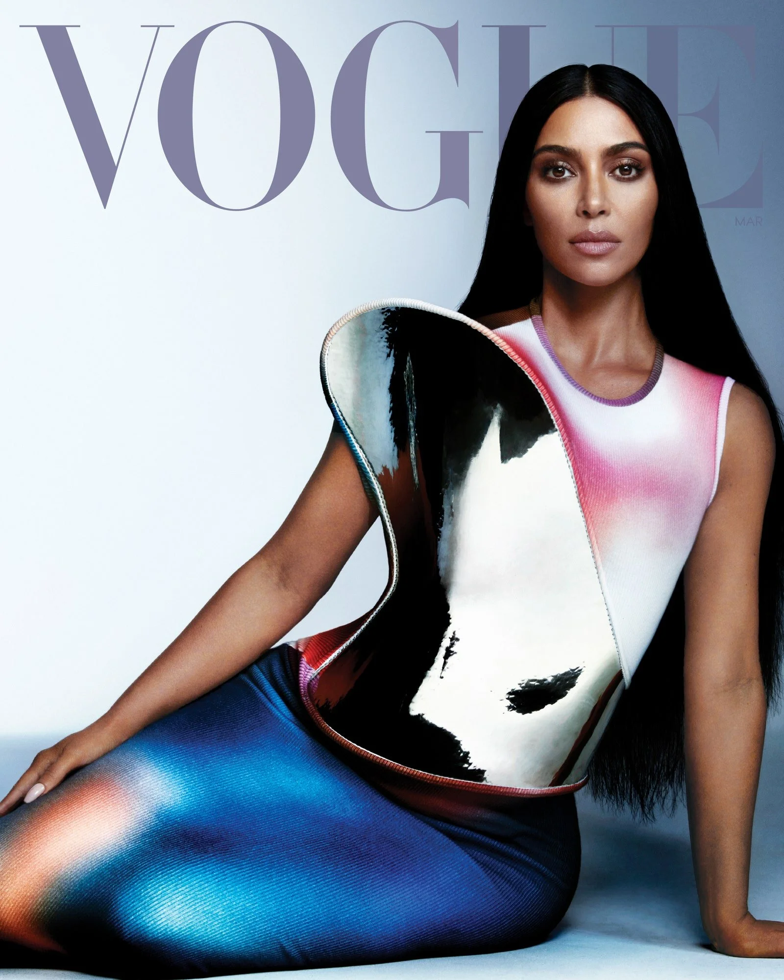 Cover of Vogue magazine featuring a woman with long black hair, wearing a colorful, artistic designed sleeveless top and a matching skirt, against a light background.