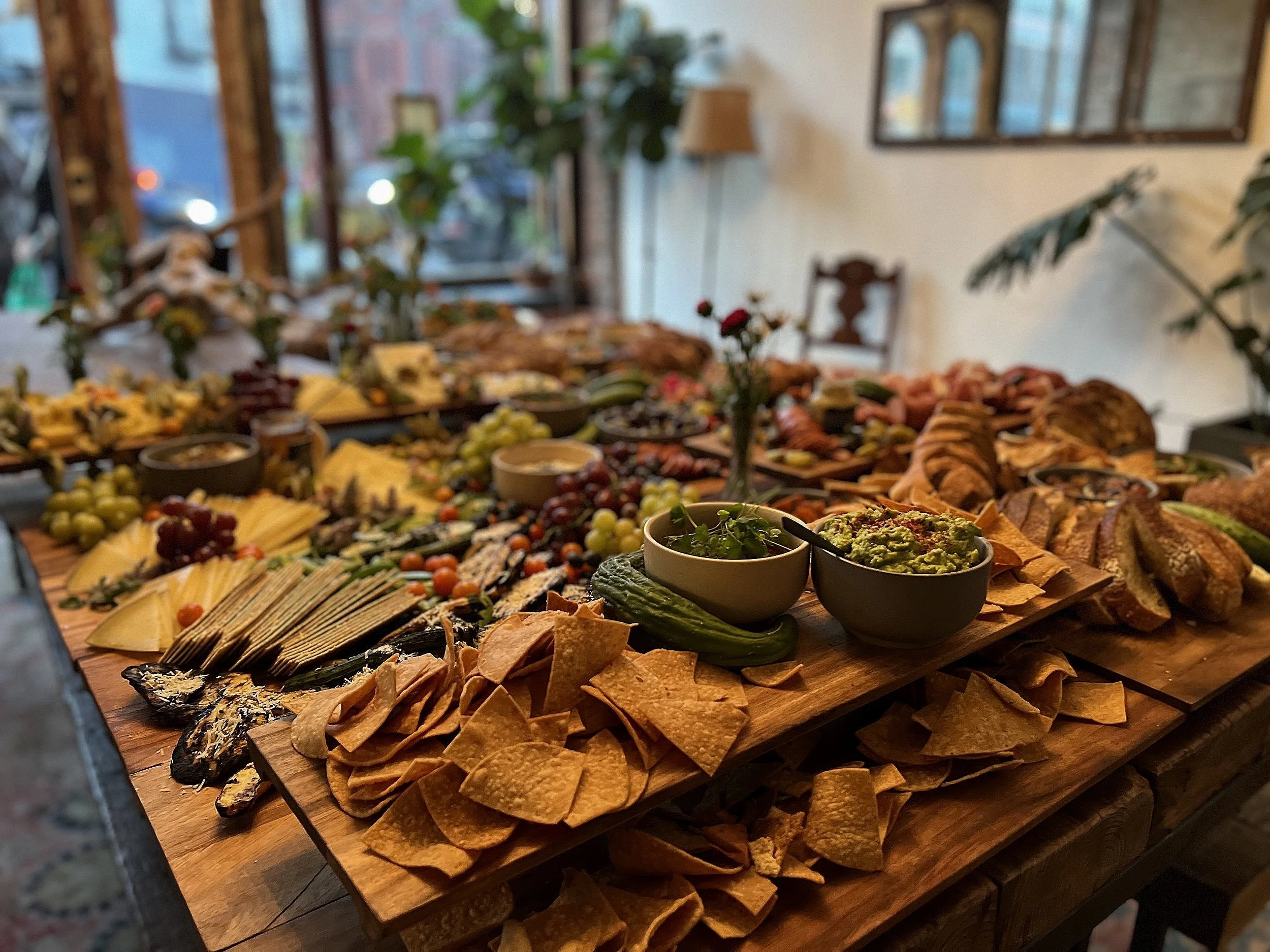 A charcuterie board filled with various cheeses, grapes, crackers, and dips in a cozy restaurant.