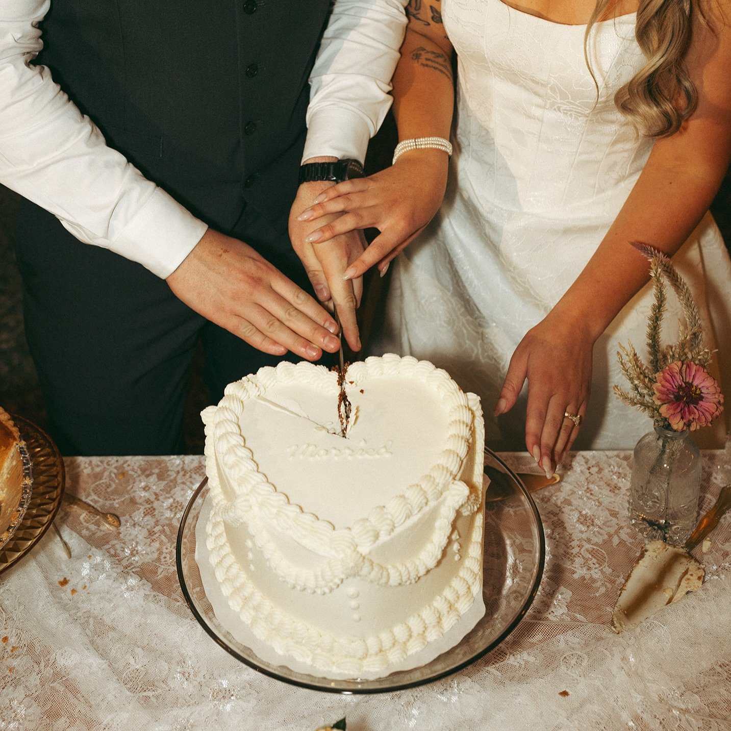 A bride and groom cut a heart-shaped wedding cake together at their wedding reception.