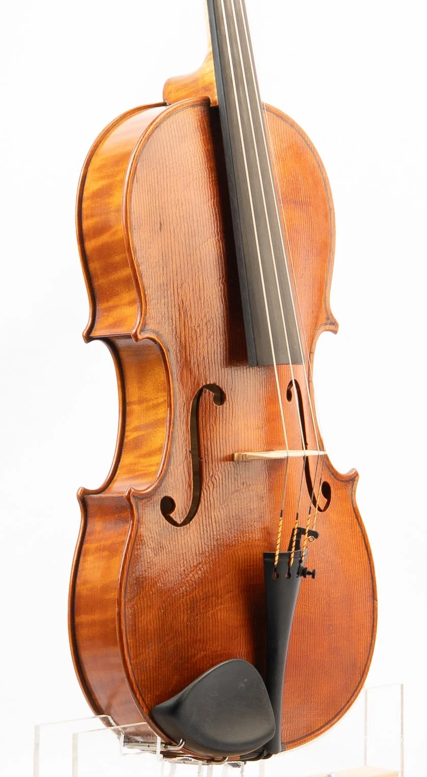 A wooden violin resting on a clear stand.