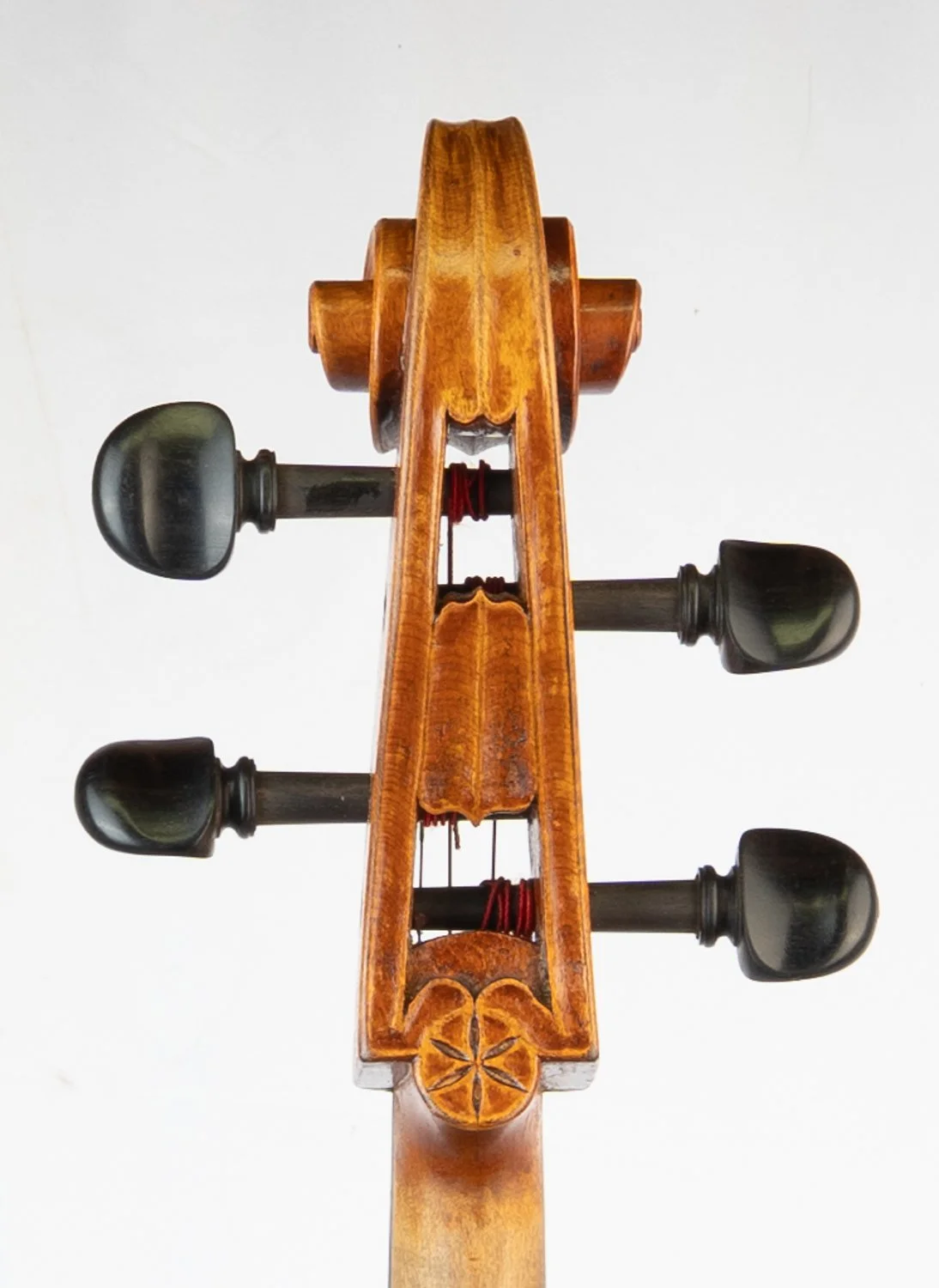 Close-up of the scroll and tuning pegs of a violin viewed from below.