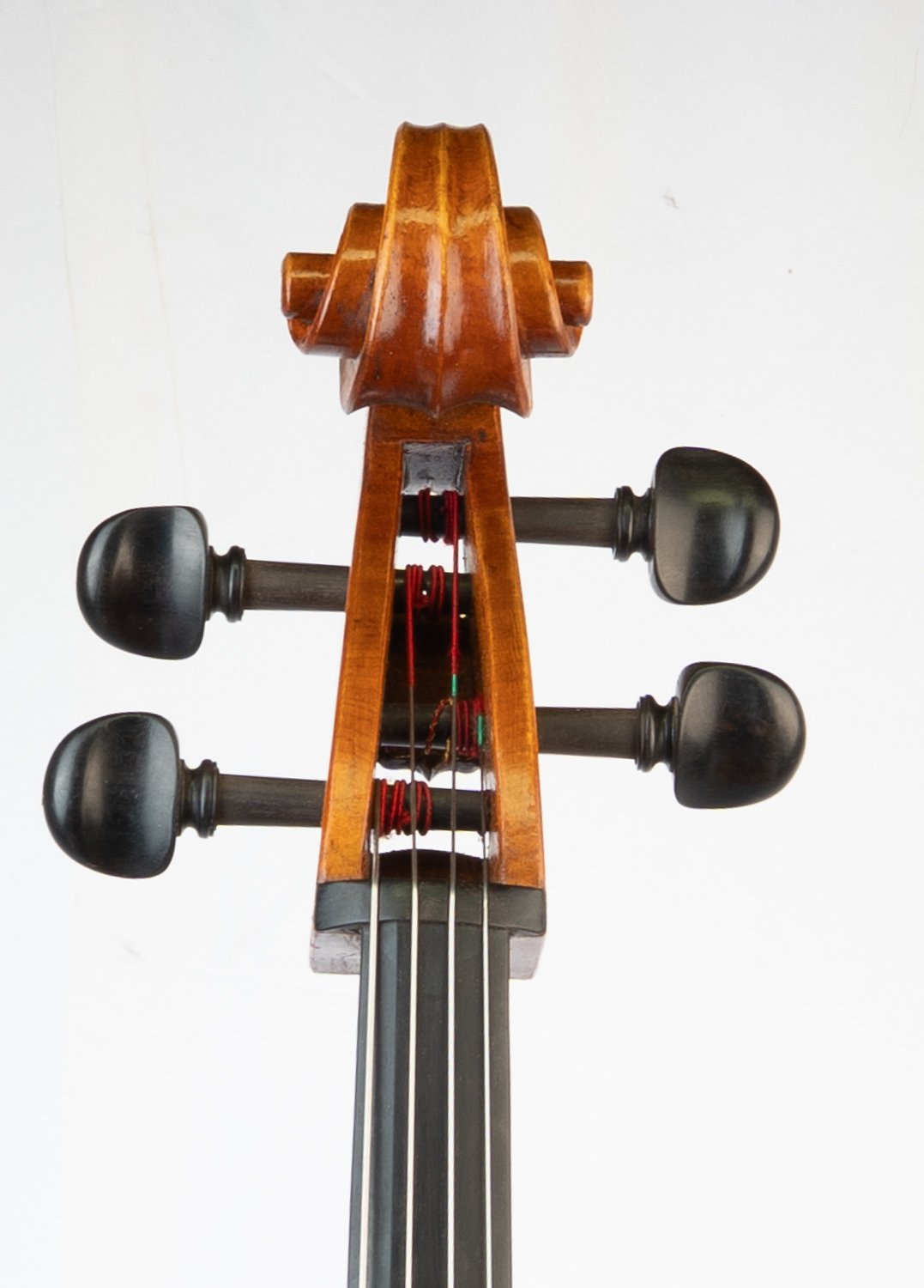 Close-up of the scroll and tuning pegs of a violin viewed from below.