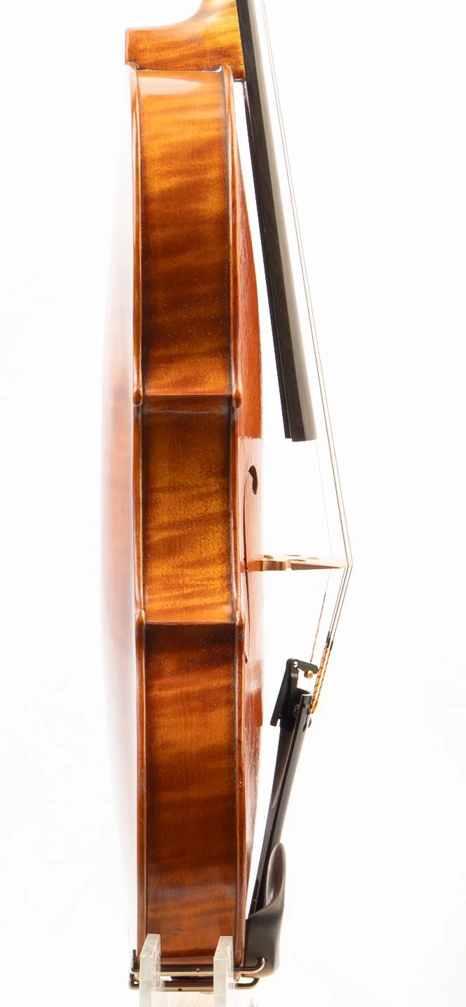 Side view of a wooden piano with a music stand and black keys, photographed against a white background.