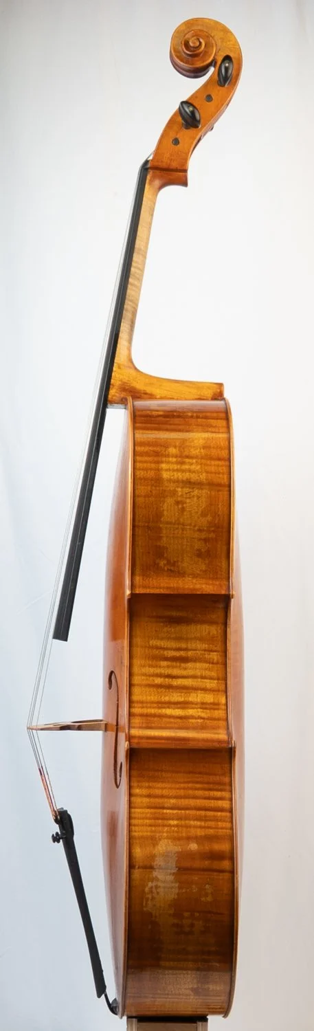 Close-up view of a wooden cello with a bow resting on it, against a plain light background.