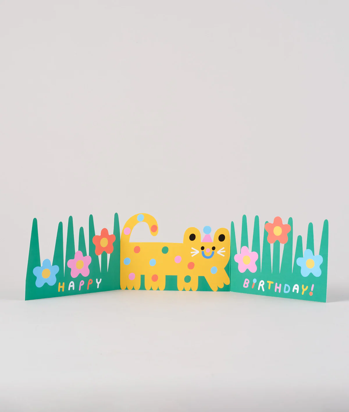 An open Cat Fold Out Card, showing a happy yellow cat walking in the green grass and colorful flowers.
