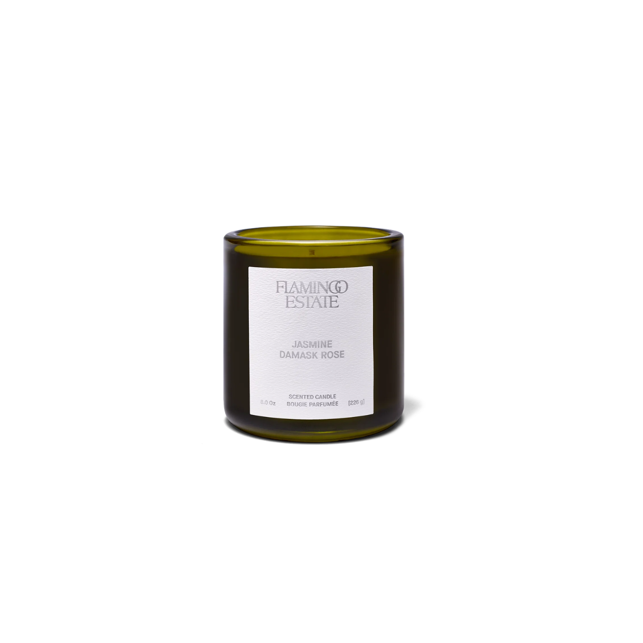 A dark green glass jar with white label containing Flamingo Estate Jasmine Damask Rose Candle.