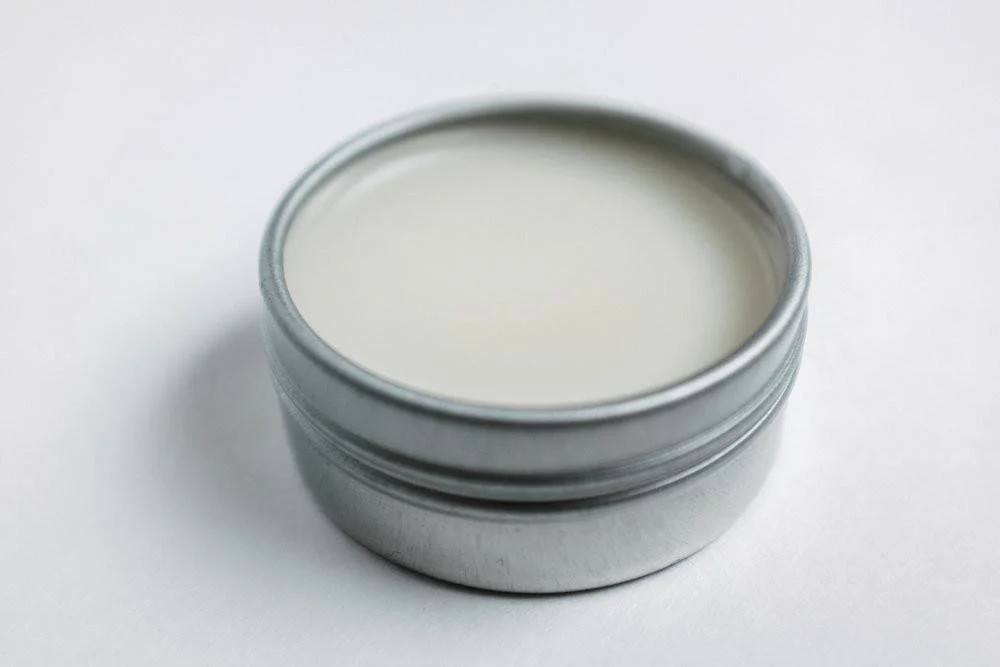 An open tin of Fresh lips Lip Balm, with white lip balm inside.