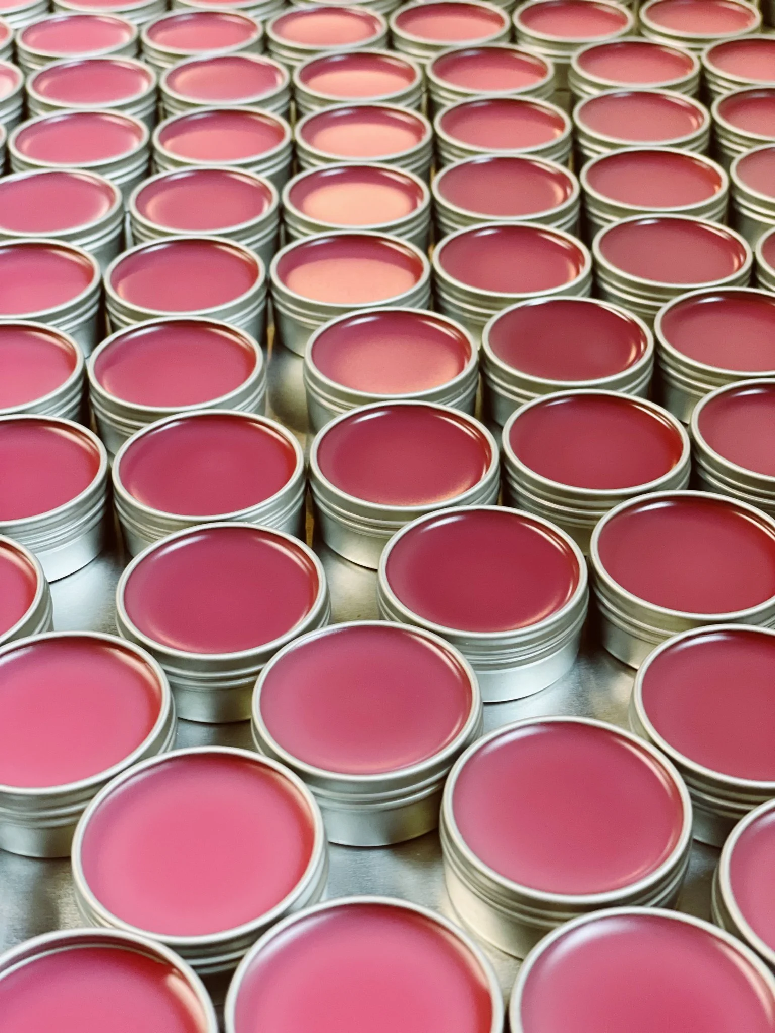 Dozens of tins of open Bell Mountain Naturals lip balms.