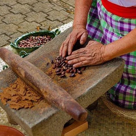 Woman shown with a rolling pin to grind the cocoa.