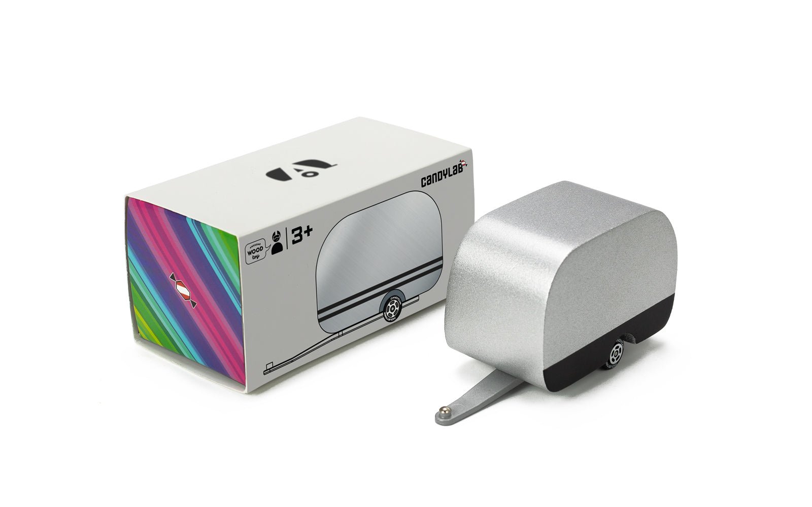 Silver and black painted wooden airstream camper with hitch attached, next to its packaging, a rectangular box.