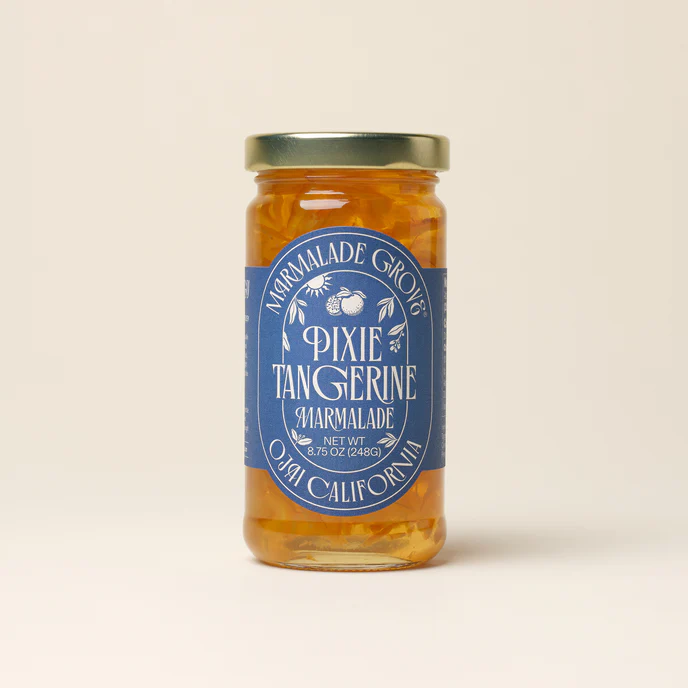 A glass jar with blue label with white print, containing Marmalade Grove "Sunrise" Pixie Tangerine Fruit Spread.