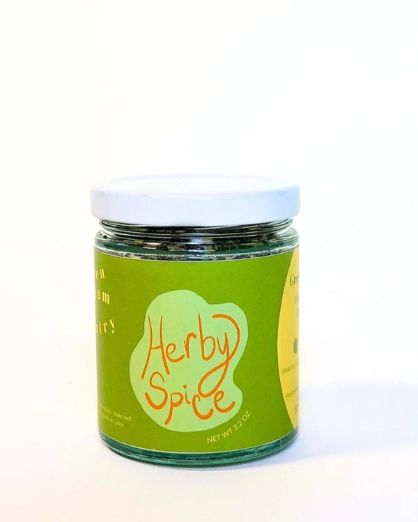 A glass jar with green label with an abstract light green graphic, the words "Herby Spice" in orange, and a white lid.