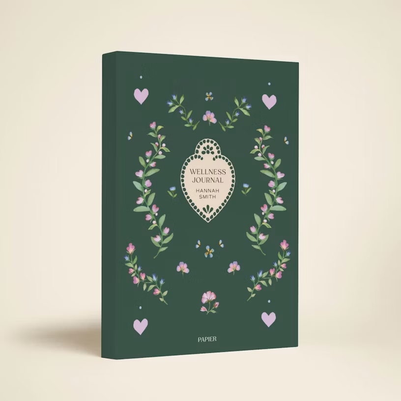 Papier Heart Locket Guided Wellness Journal, a journal with a green cover with a design of pink flowers and a heart locket in the center.