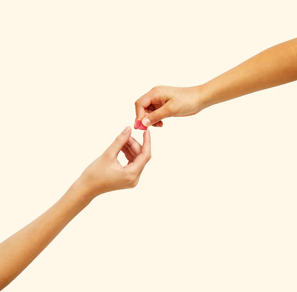 Two arms reached out, with one hand giving a sour watermelon mochi gummy to the other hand.
