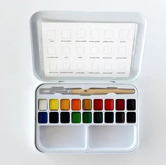 An open container of the Emily Lex Watercolor Paint Set, revealing 18 different watercolor paints.