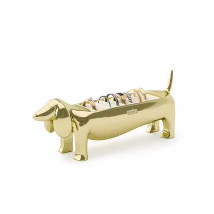 A brass ring holder in the shape of a dachshund, with a velvet padded base for rings.