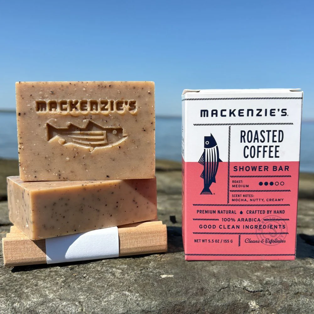 A pink and white box containing MacKenzie's Roasted Coffee Shower Bar, next to two unpackaged bars of Roasted Coffee Shower Bar.