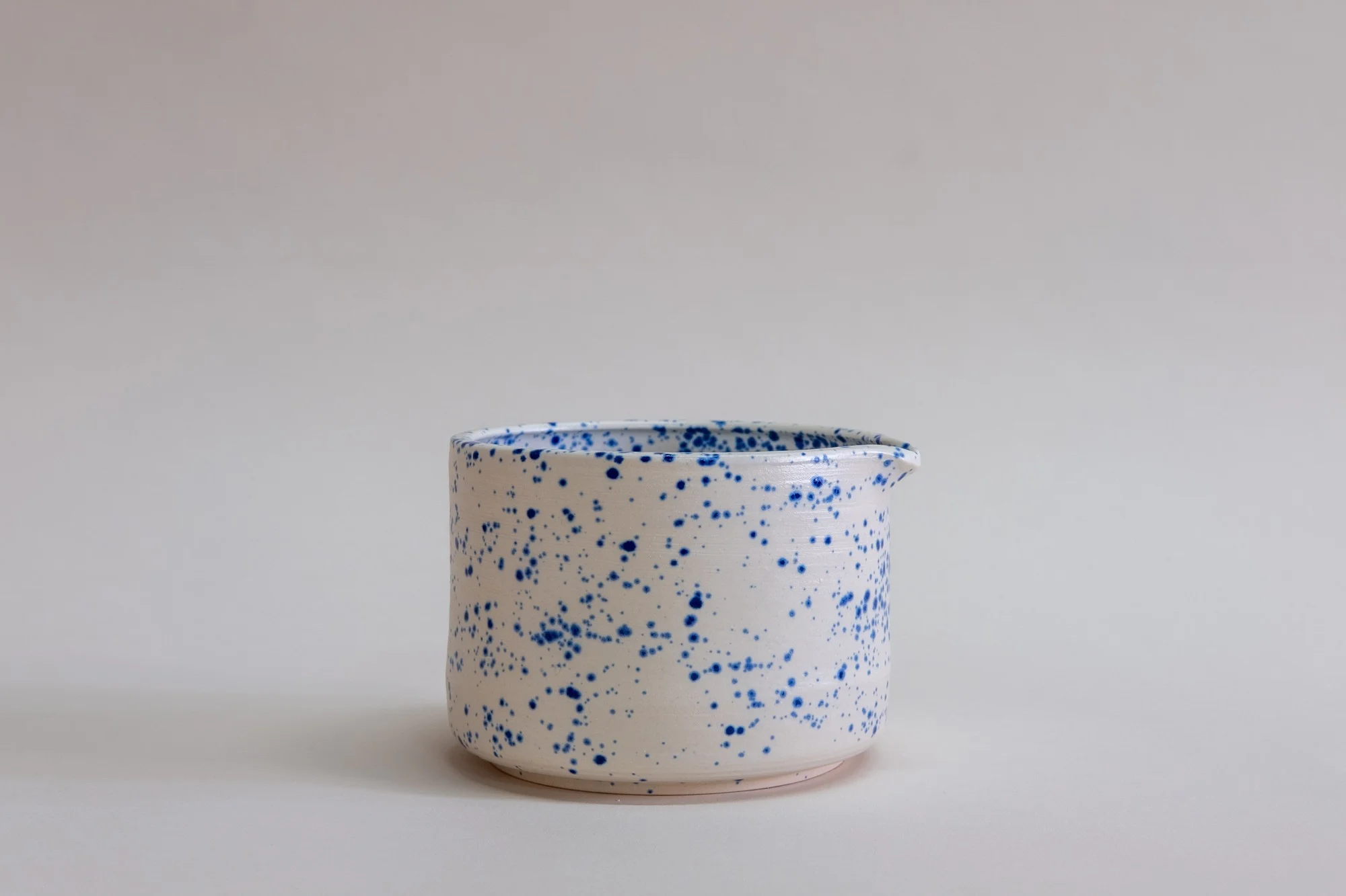 Utility Objects Speckled Blue Chawan Bowl, an off white ceramic bowl with a blue speckles and a spout.