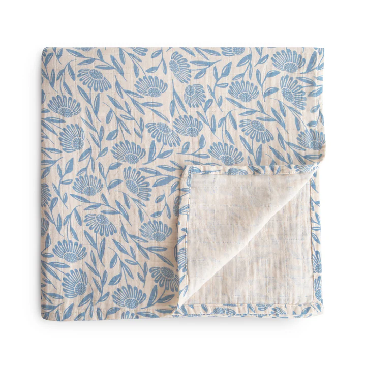 A cotton muslin swaddle with a blue floral pattern folded into a square.