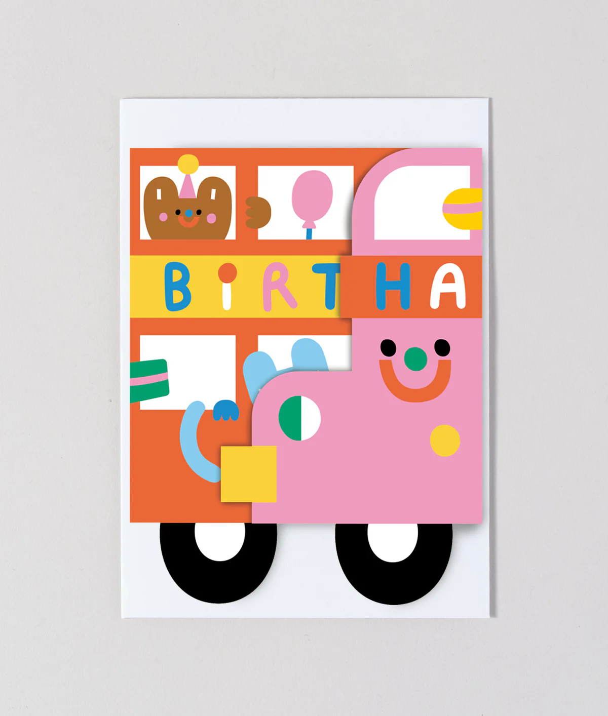 A folded orange bus birthday card in front of a white envelope.