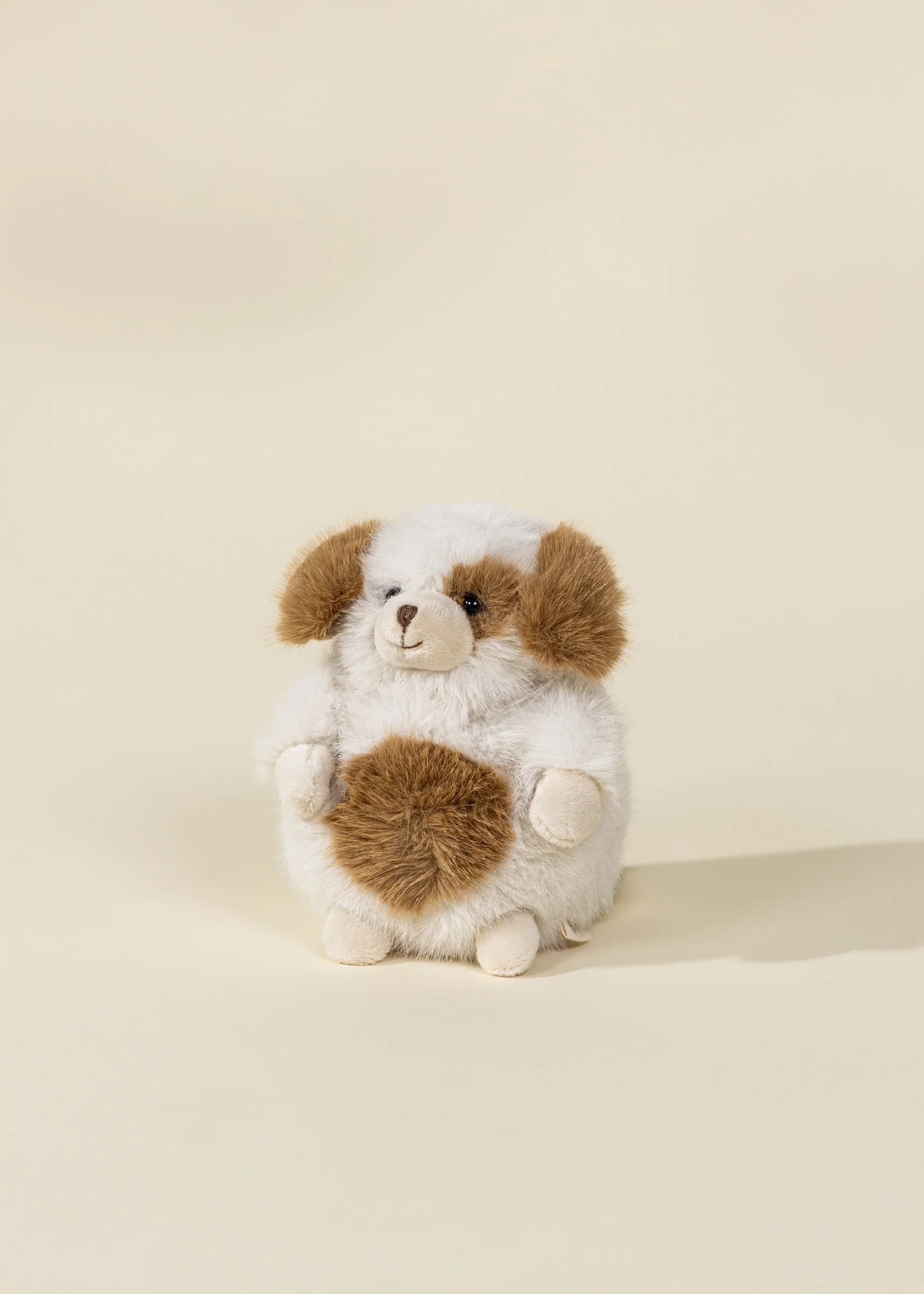 A brown and white plush dog with black eyes and floppy ears.