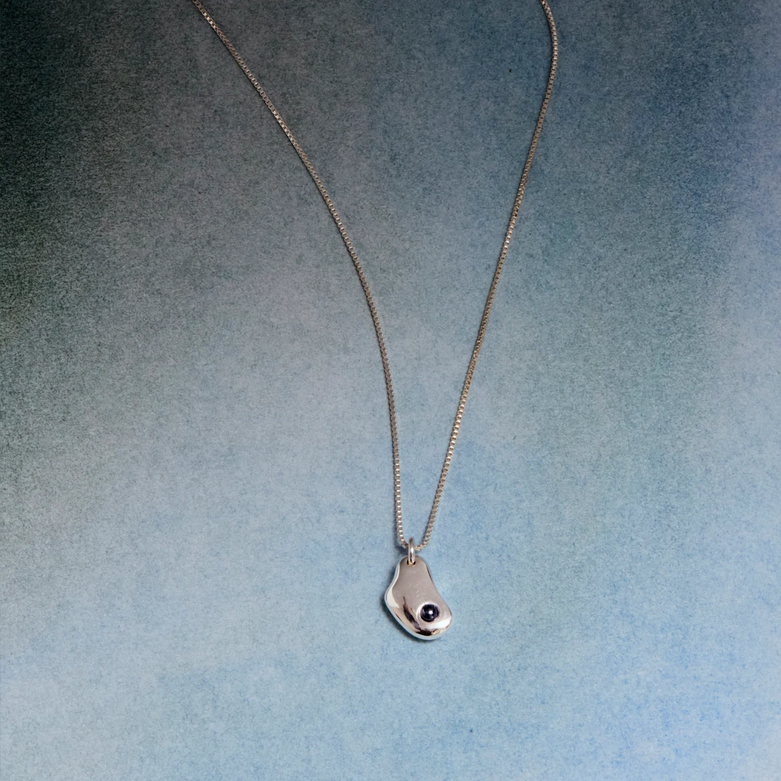 An abstract sterling silver pendant with a hematite stone on a sterling silver chain.