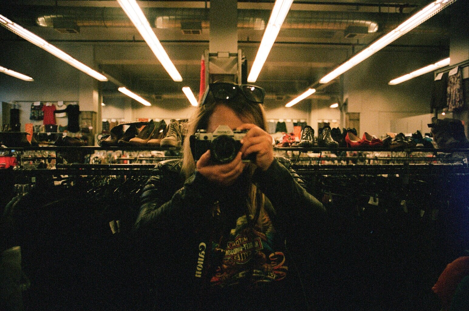 ANDREA VODICKOVA taking a selfie in mirror at a thrift store