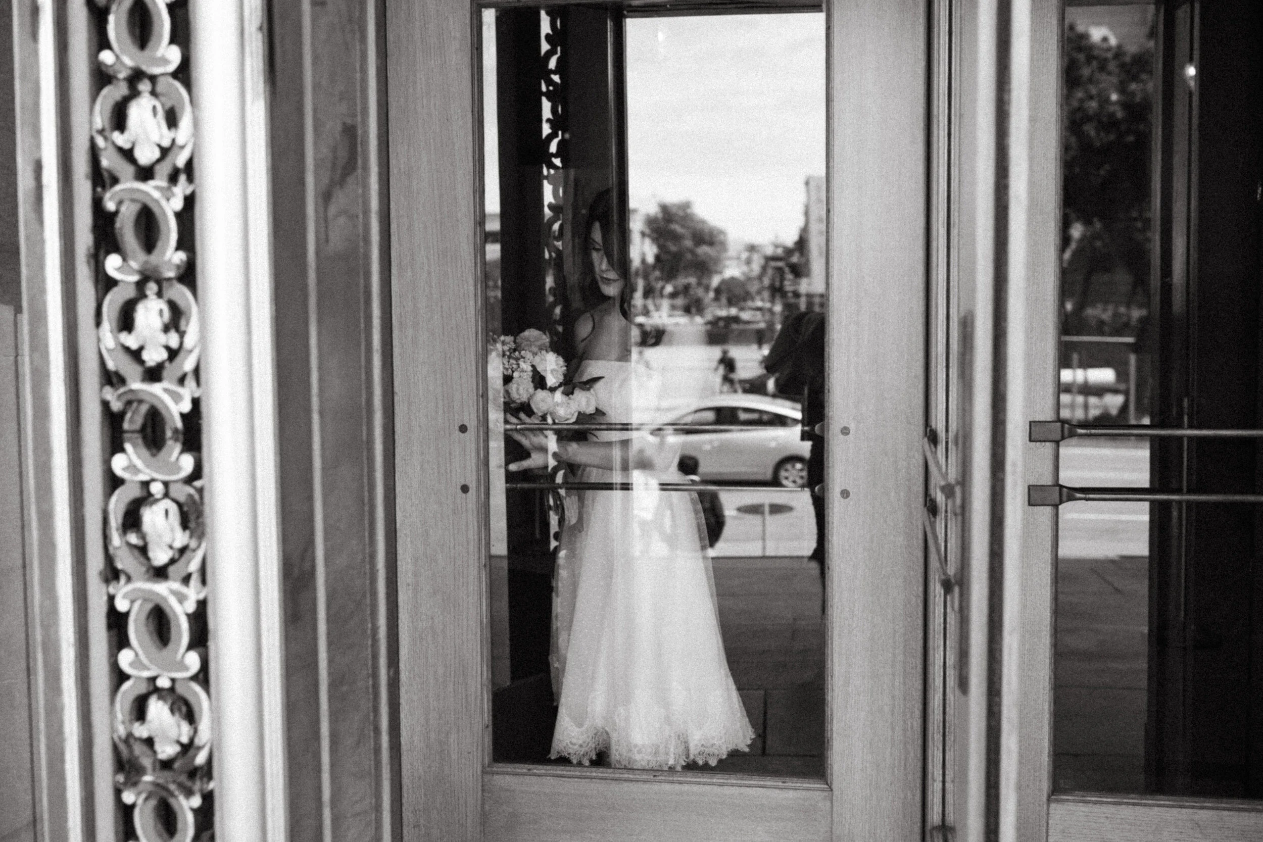 a bride walking through revolving door in black and white 10 reasons to elope by Andrea Vodickova