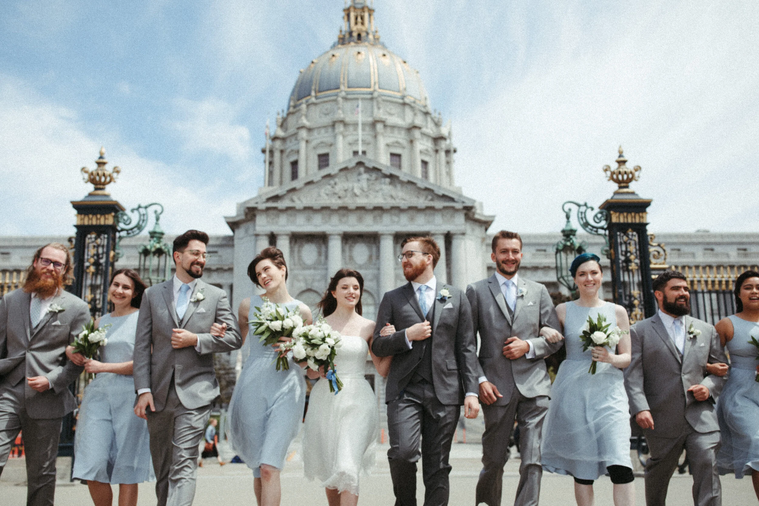 newlywed couple and the bridal party walking together with SF city hall in the back San Francisco California wedding and elopement photographer Super 8 Polaroid film video by Andrea Vodickova