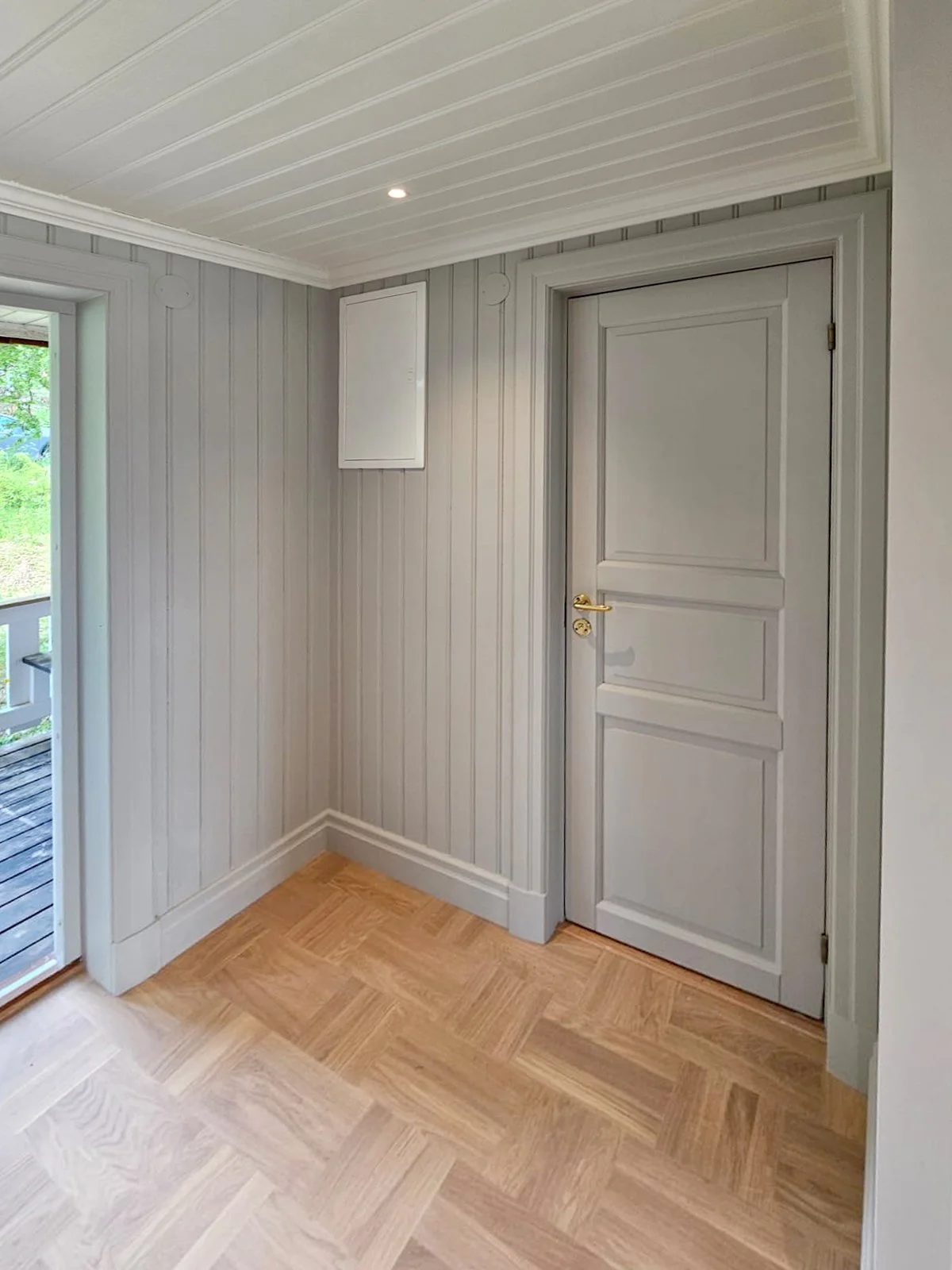 Hall med panel på väggarna och spegeldörr