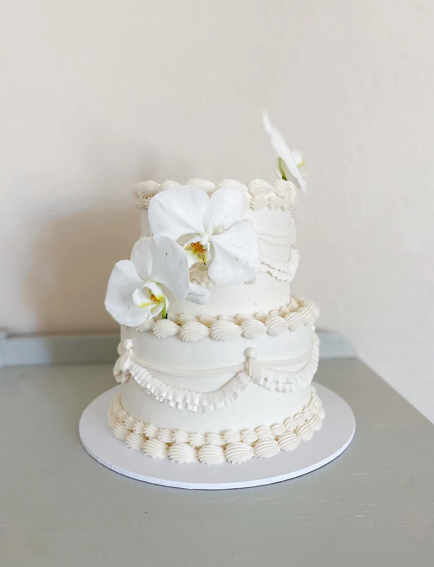 Vintage Piping &amp; Orchids 🤍
Another fun wedding cake for the week!! 

6&rdquo; | 8&rdquo; Shorty Cake 
Lemon Poppyseed cake layers, filled with Raspberry filling &amp; frosted in a vanilla buttercream.