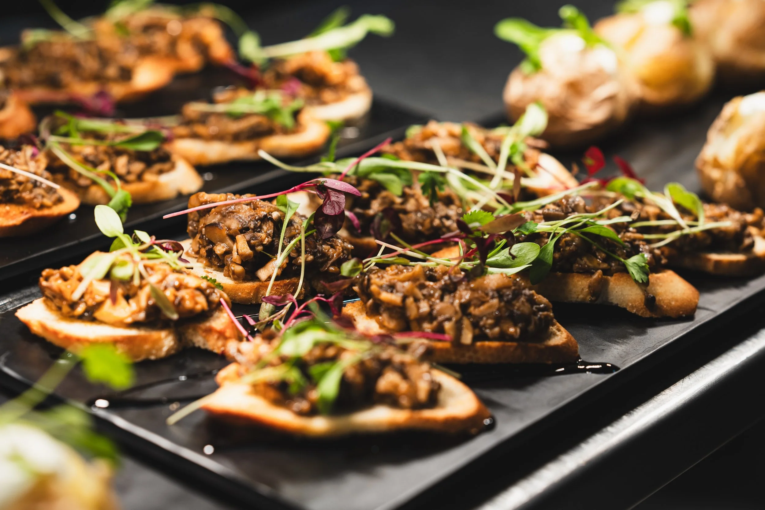 Behind the scenes capturing the incredible depth of a beautifully executed rustic spread. It&rsquo;s all about the contrast here, the earthy, rich textures of wild mushrooms paired against the clean snap of fresh microgreens and a crisp base. Elevati