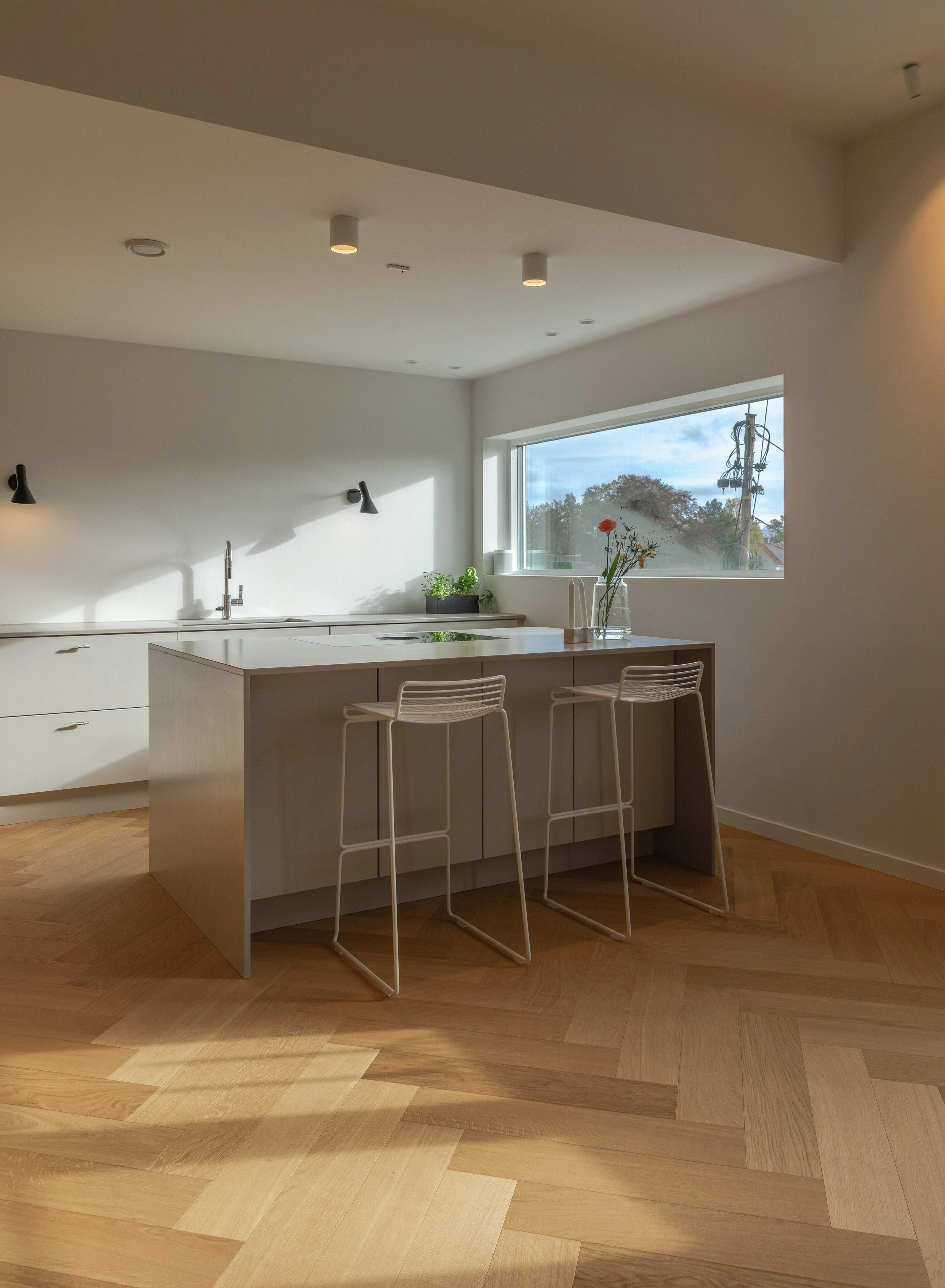 Kjøkkenet er plassert i det nyere tilbygget fra 1968, der de lyse skapmodulene utgjør en vakker kontrast til det plassbygde eikeinventaret og fiskebensparketten i eik.