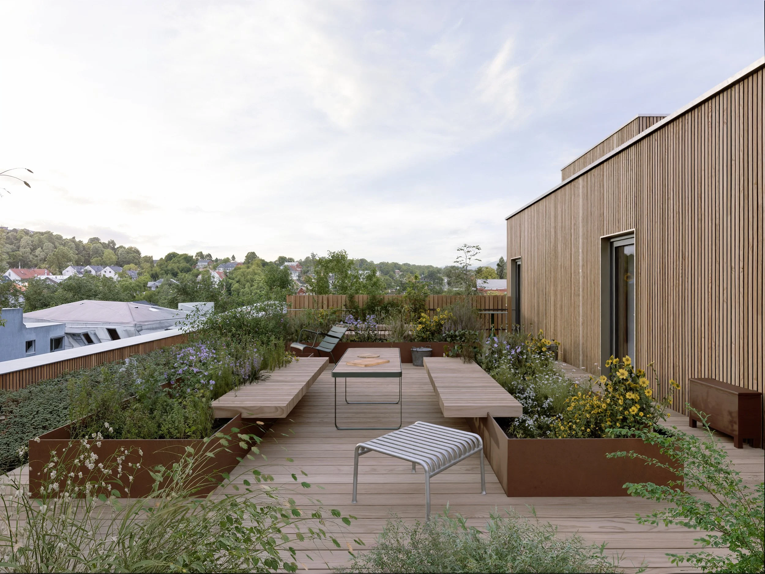 Atmosfærisk. Trepanelet går igjen på et inntrukket heisoppbygg på taket der det danner et varmt bakteppe for et rikt beplantet fellesareal.  