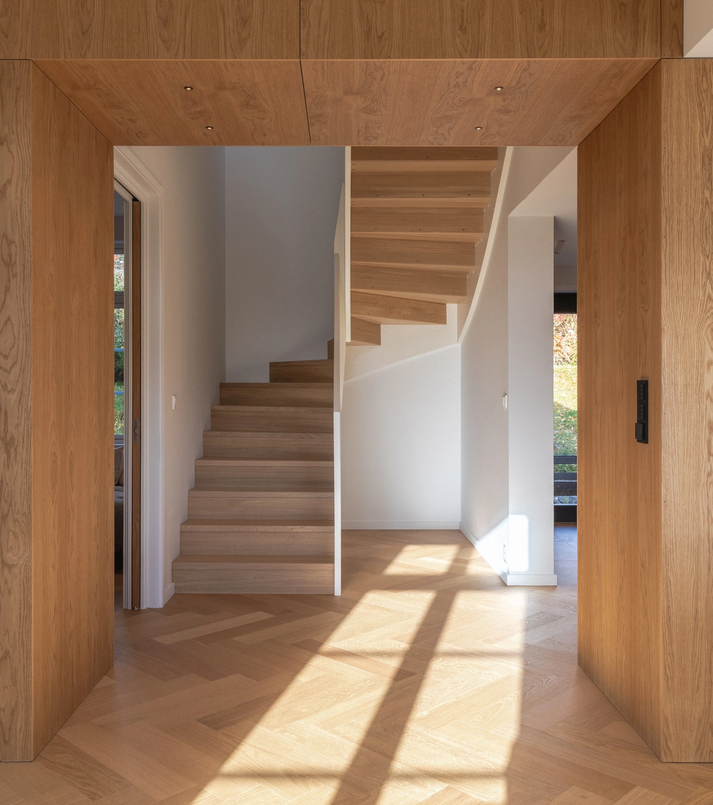 Trappeløpet er lagt midt i etasjen, der vinduene i de tilstøtende rom sender dagslyset gjennom leiligheten og bidrar til å lyse opp gangpartiet.