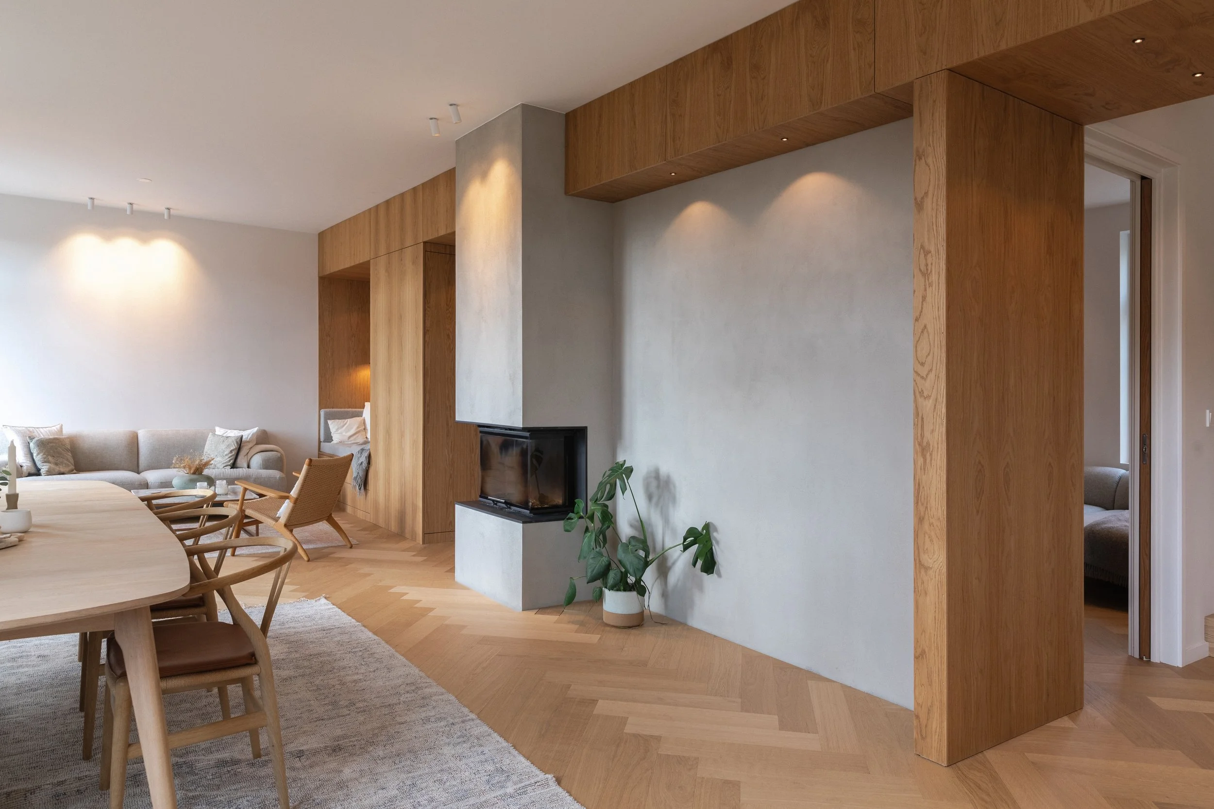 Veggpartiet som strekker seg på langs i første etasje, er bygget som en tykk funksjonsvegg med integrerte løsninger. Ved siden av peisen er det lagt inne en nisje med plass til å henge opp kunstverk.