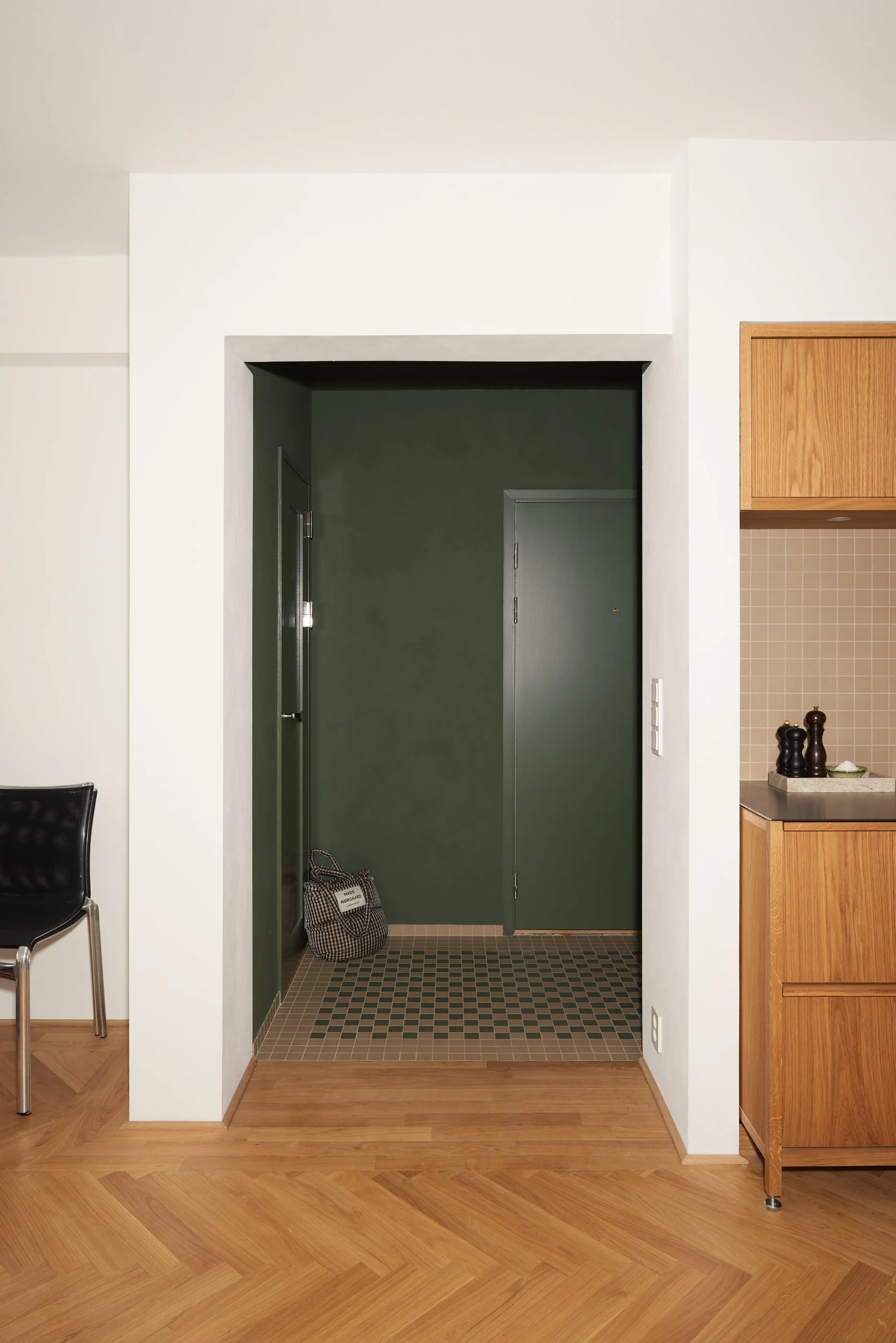 Takk og vegger er malt i en dyp grønnfarge som akkompagneres av et sjakkmønstre flisegulv som utgjør en kontrast i overgangen ut til de hvitkalkede veggene i oppholdsrommet. 