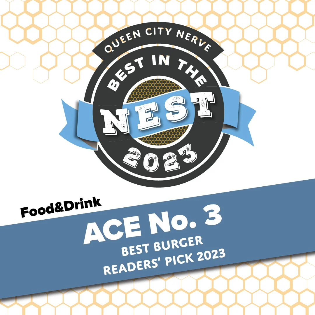 Badge with honeycomb pattern background, featuring a circular emblem that says "Queen City Nerve," "Best in the NES T 2023," and a blue banner that reads "Food & Drink ACE No. 3 Best Burger Readers' Pick 2023."