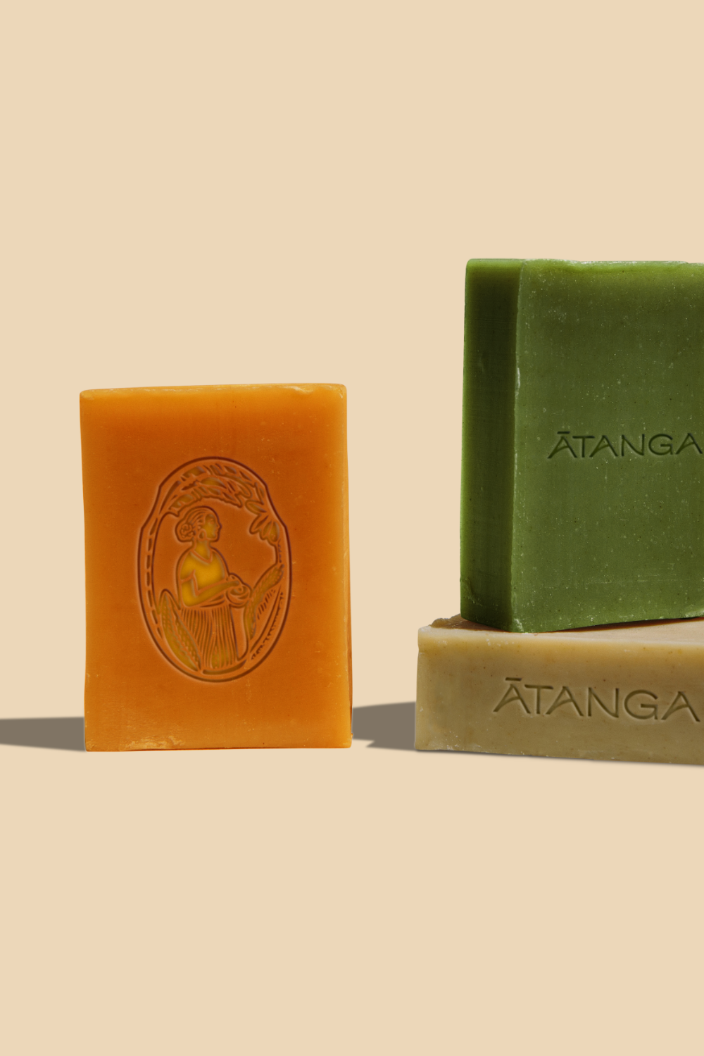 Trois barres de savon colorées sur un fond beige.