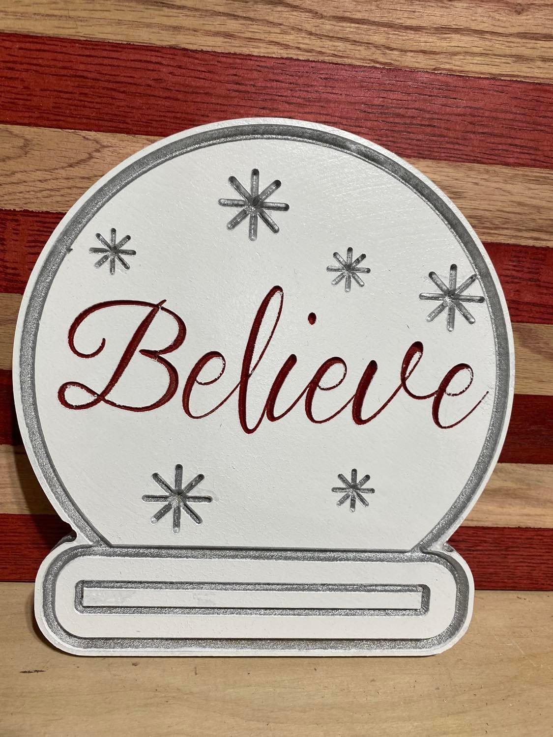 Believe snow globe. This piece is made to look like your favorite snow globe. Red, silver and white measuring 8" x 8" x 1/2" made out of MDF. A fun decoration for the holidays.