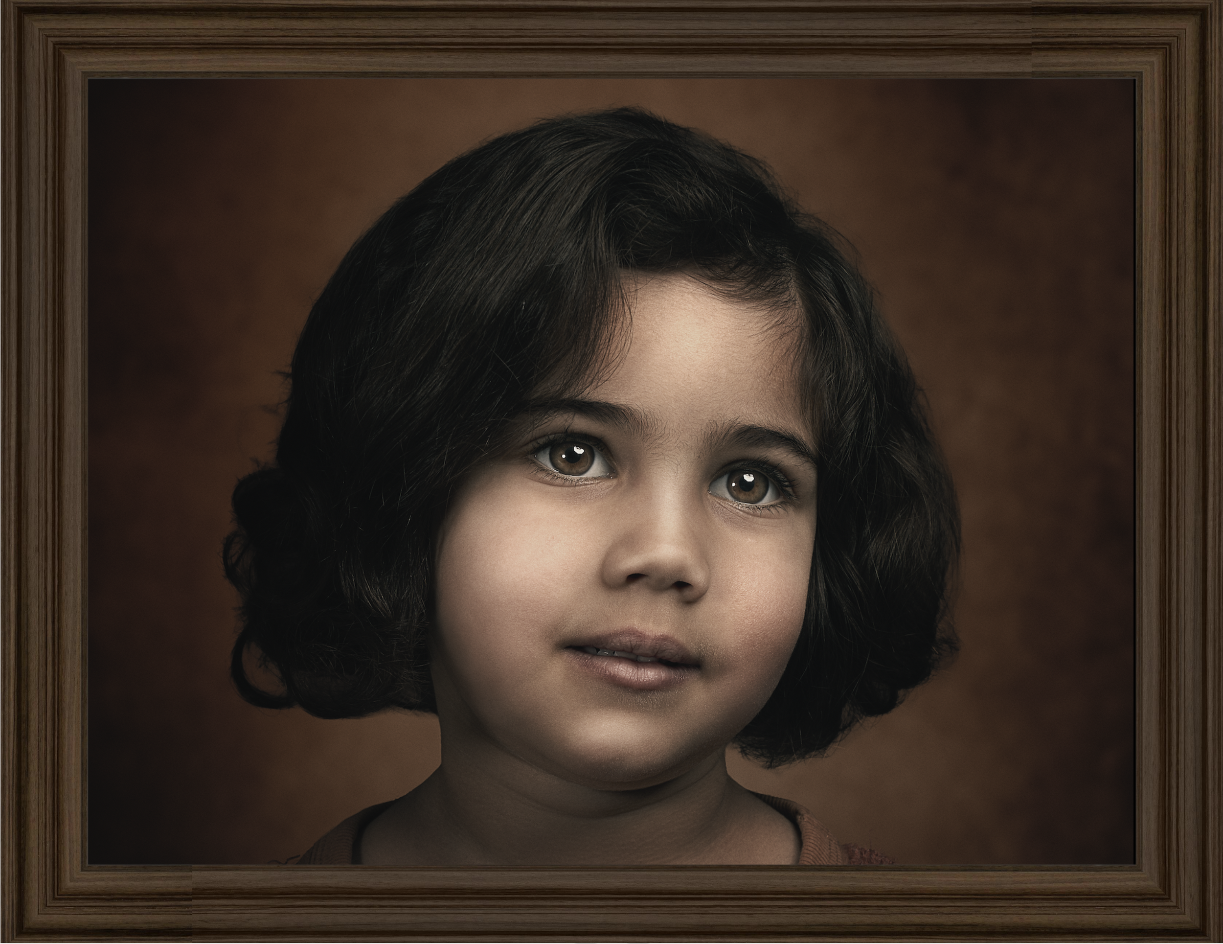 A portrait of a young girl with dark, curly hair and brown eyes, framed in a brown wooden frame with a brown background.
