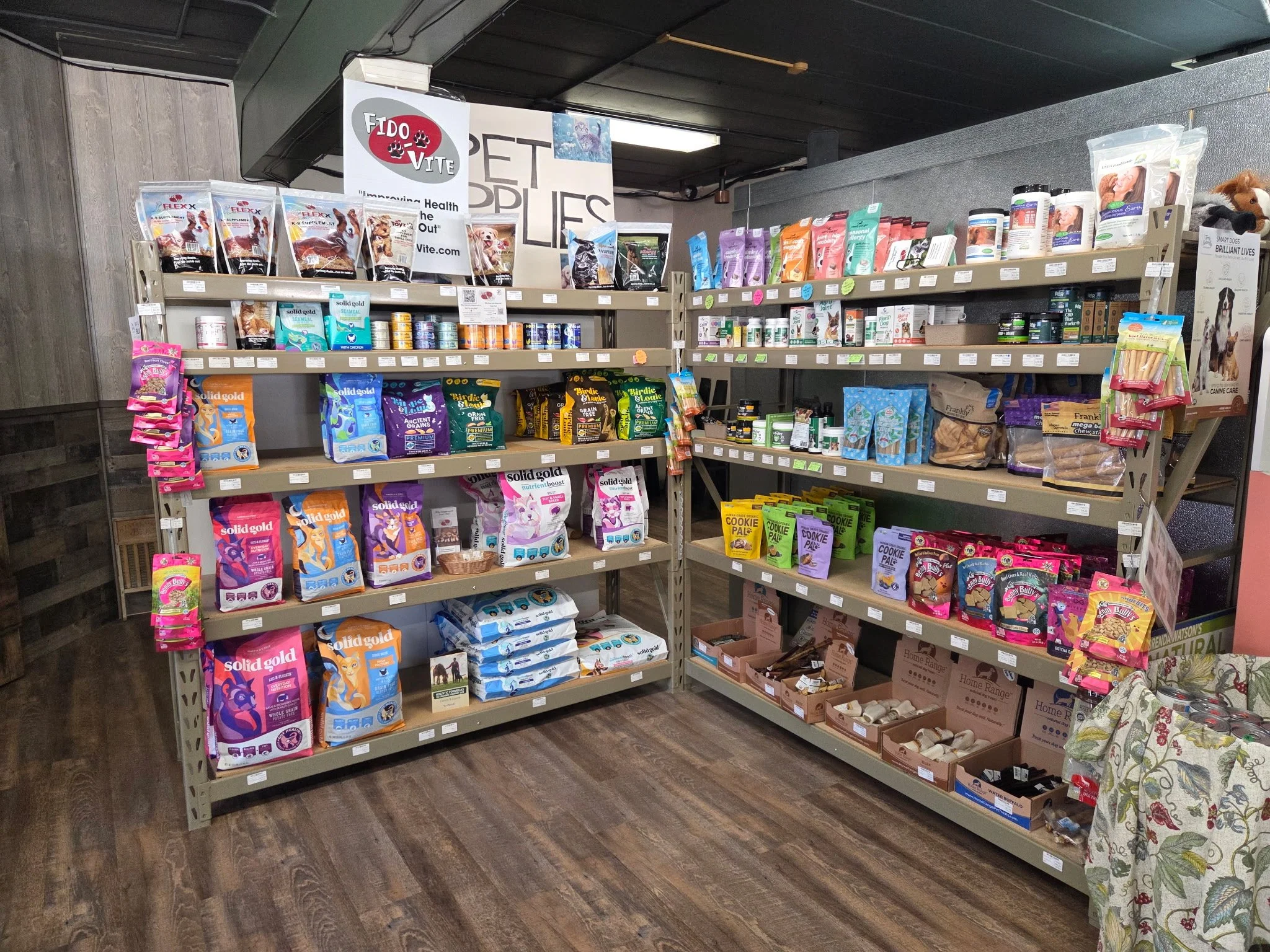 Shelves in a pet store displaying various bags of pet food, treats, and supplies.