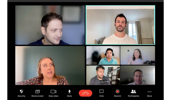 Screenshot of a virtual meeting with seven participants, including a woman in a floral top, a man with facial hair in a white shirt, and others in various settings.