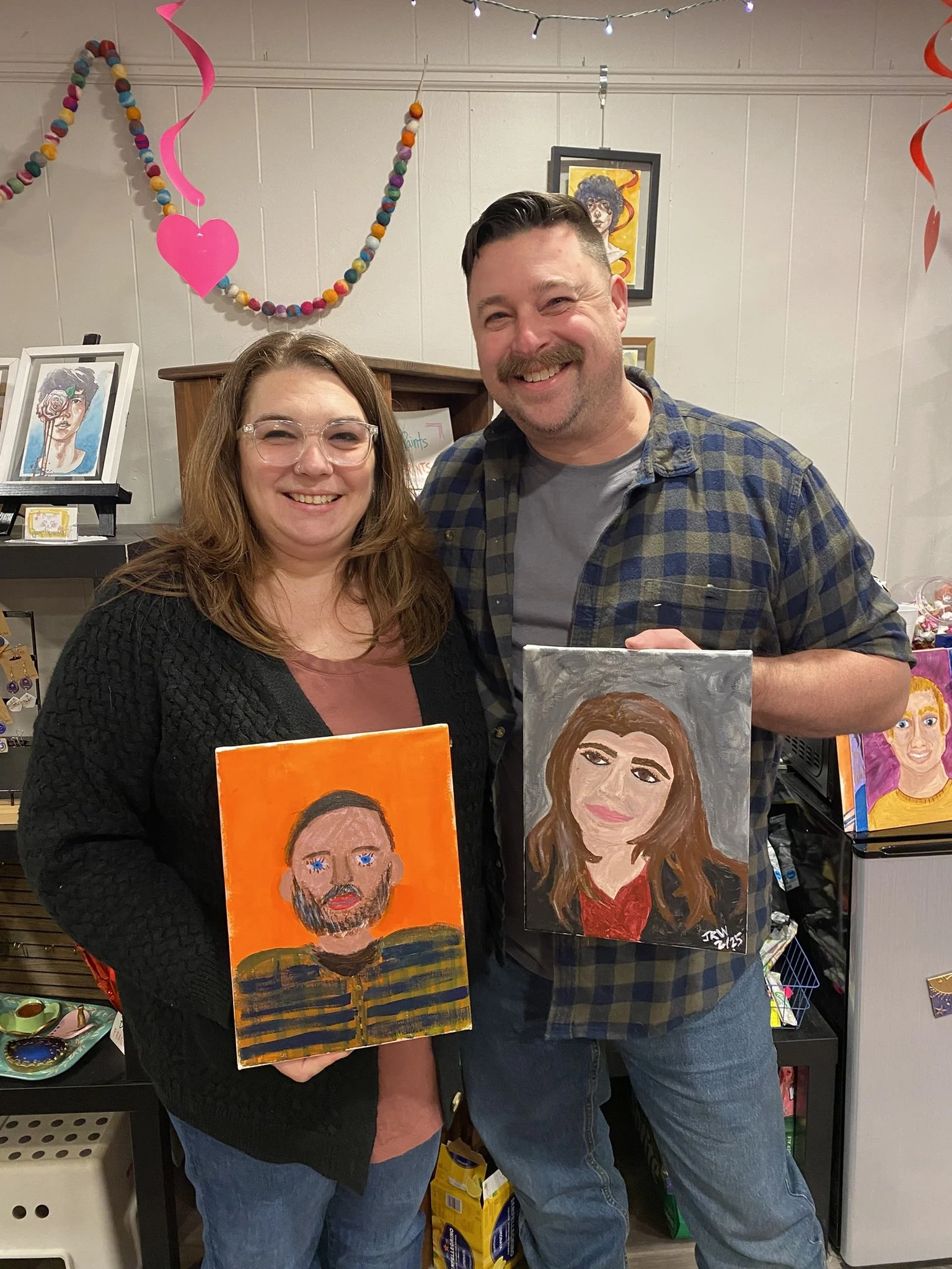 photo of a couple holding paintings of themselves