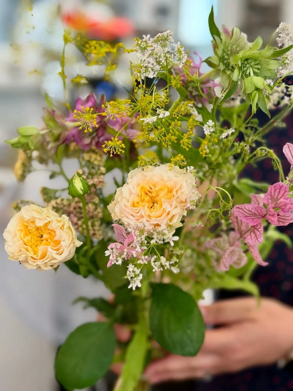 A colorful bouquet of various flowers including yellow, pink, white, and green blossoms.