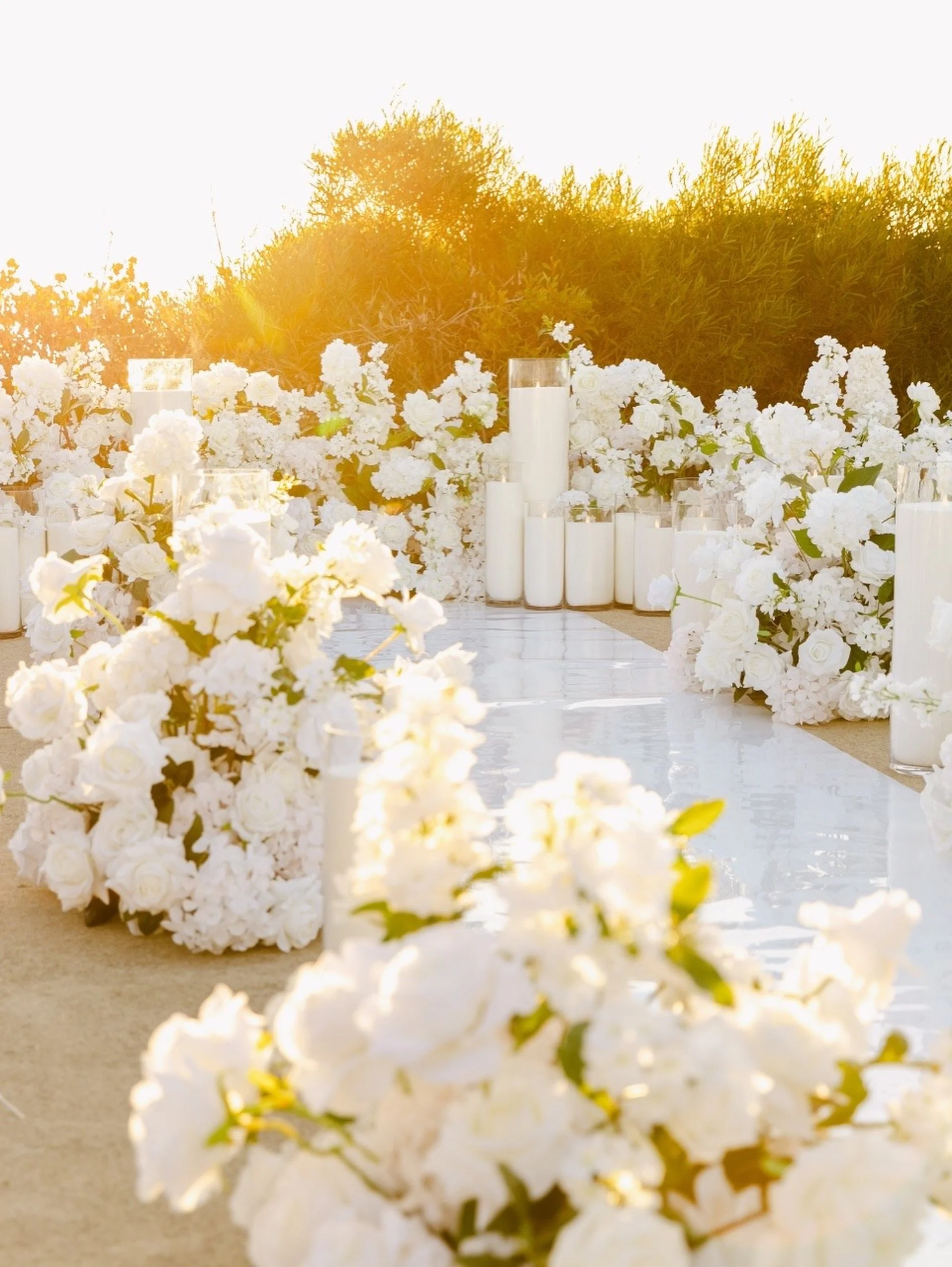 A aisle decorated with white flowers and candles, leading to a proposal setup outdoors during sunset.  Candle styling by Candlescapes, Perth Candle Styling & Hire.