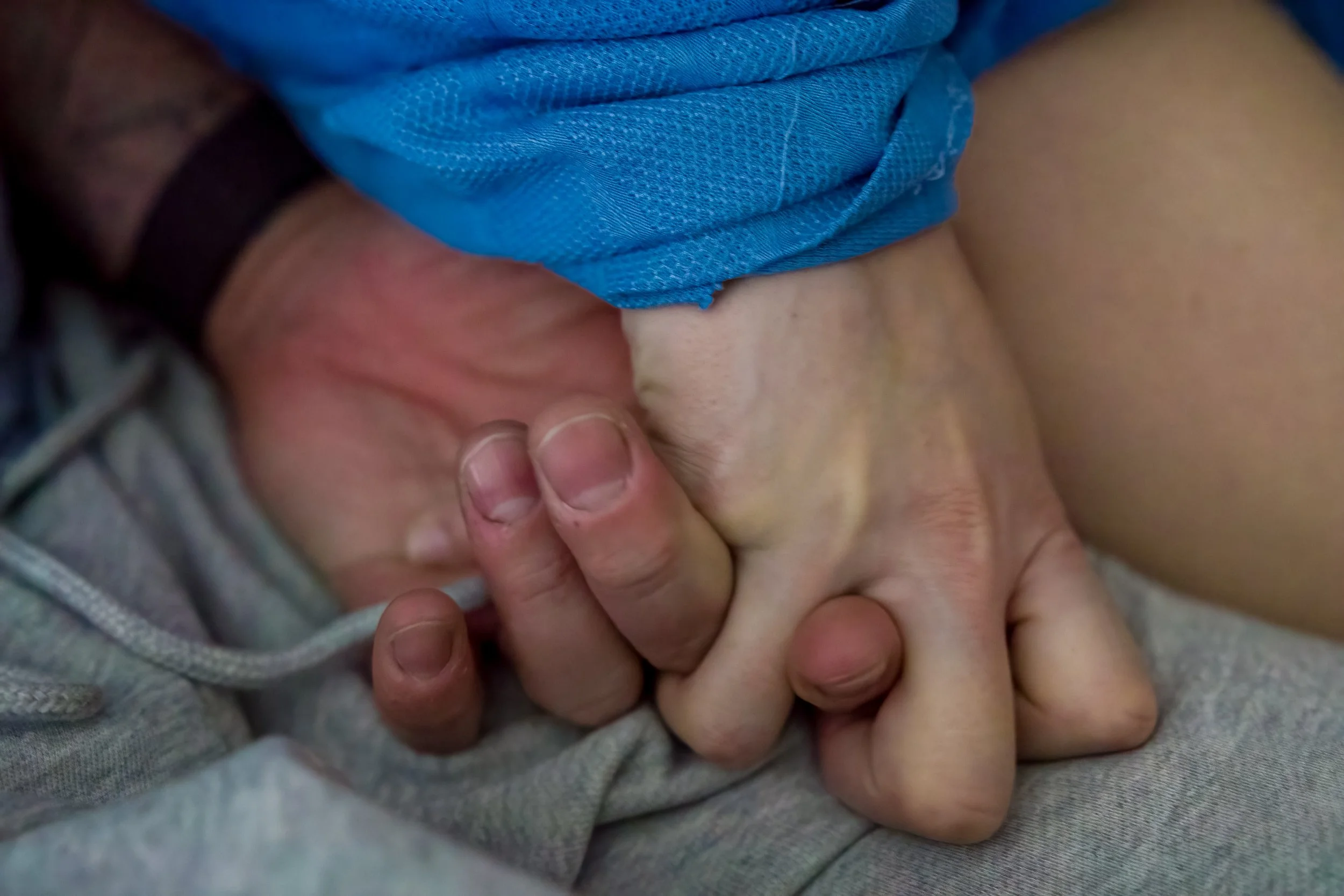 a woman in labour holds her husbands hand giving birth