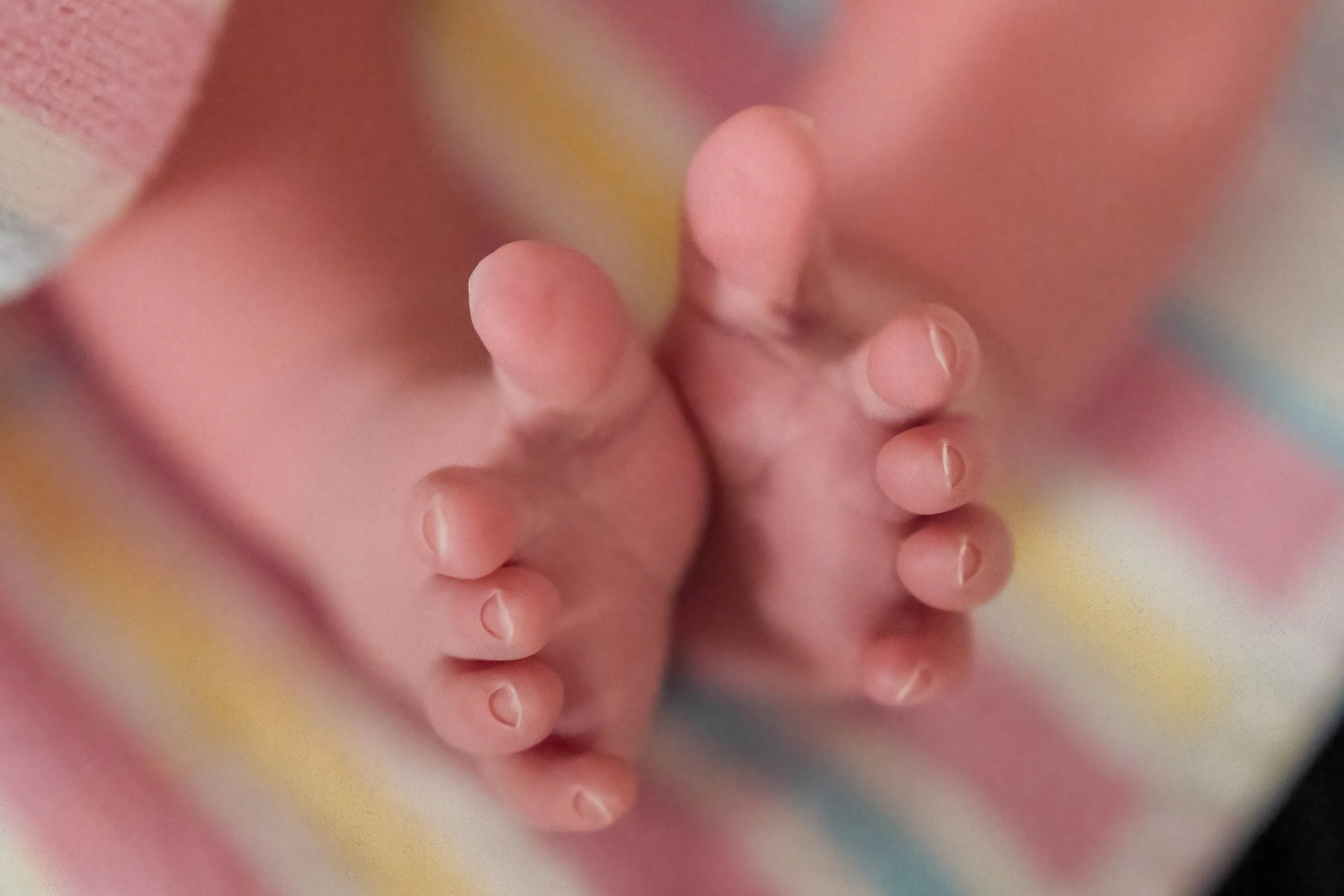 Close-up of a baby's feet on a soft, colorful blanket.