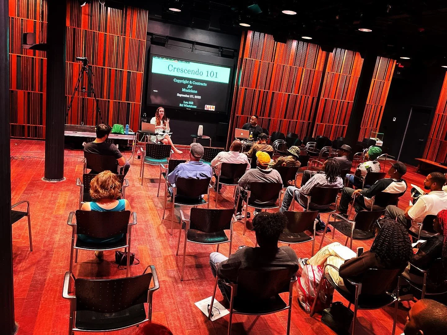 Crescendo workshop participants seated in rows facing presenters and a projection screen at the New Orleans Jazz Museum.
