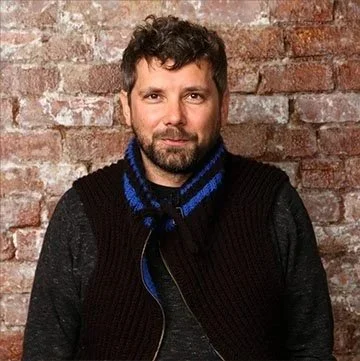 A headshot of Petr Verner of the Jazz Foundation of America in front of a brick wall.